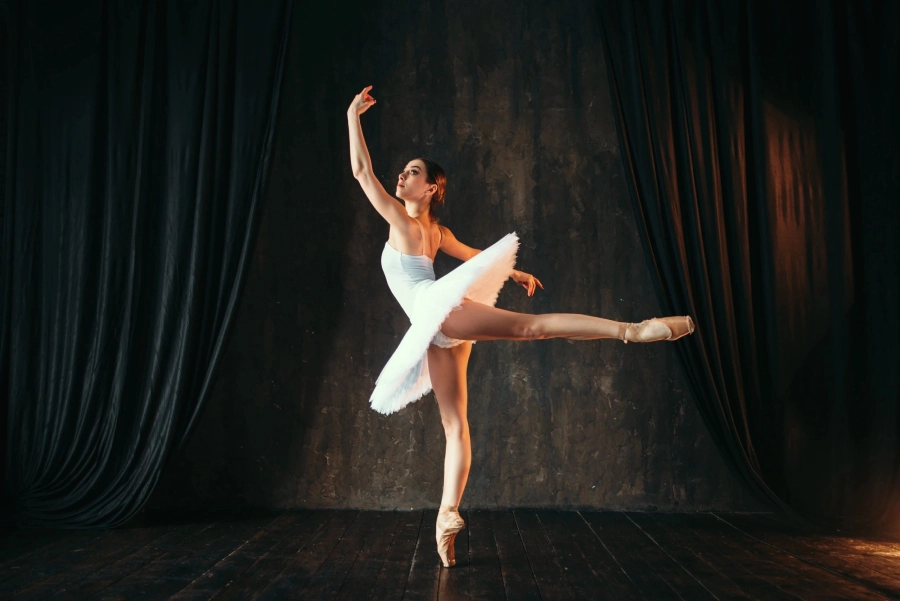 A woman in white dress and black shoes doing ballet.